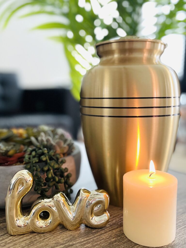 Photo of remation urn next to a burning candleand 